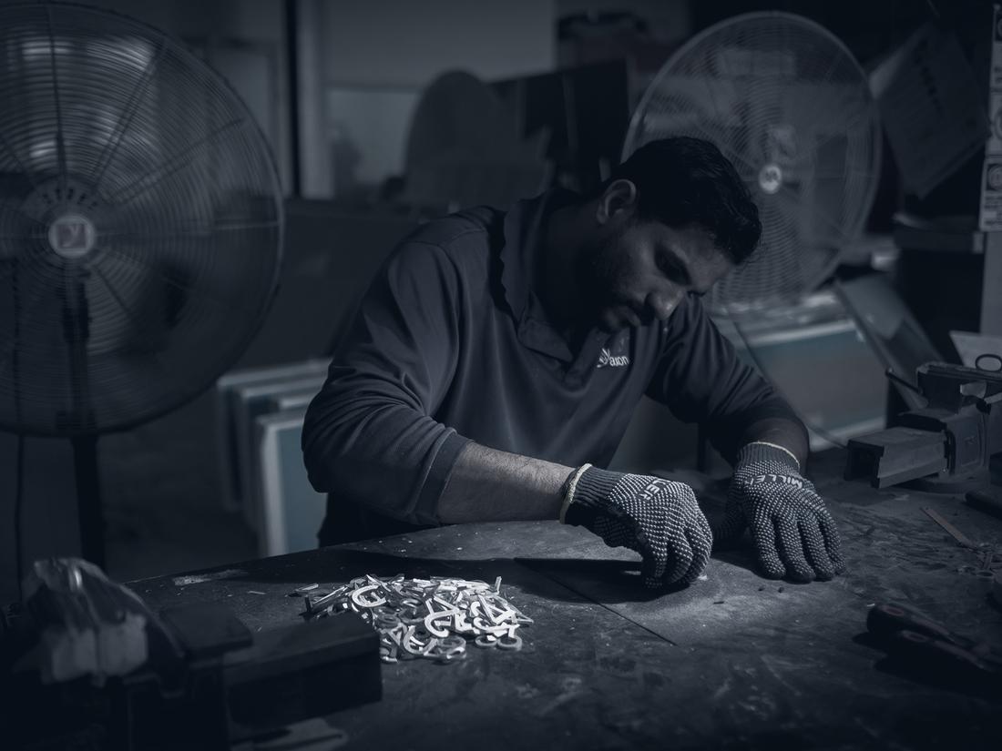 AXON fabricator hand-finishing metal letters in the production facility